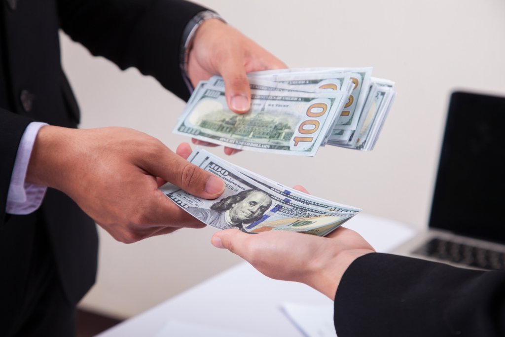 Person negotiating car price with cash