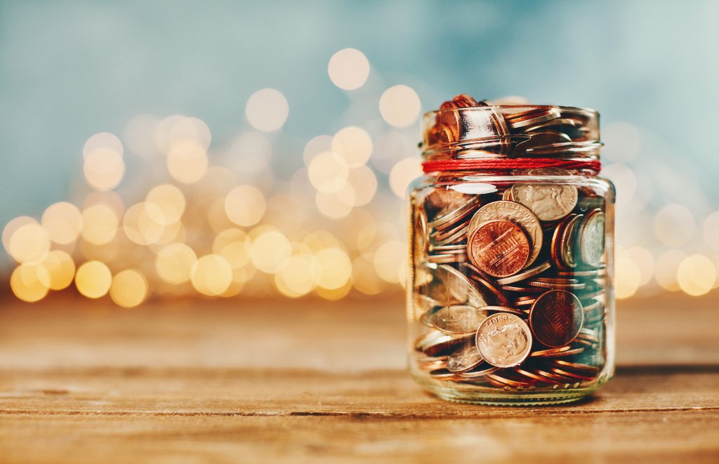 jar full of coins in front of holiday lights