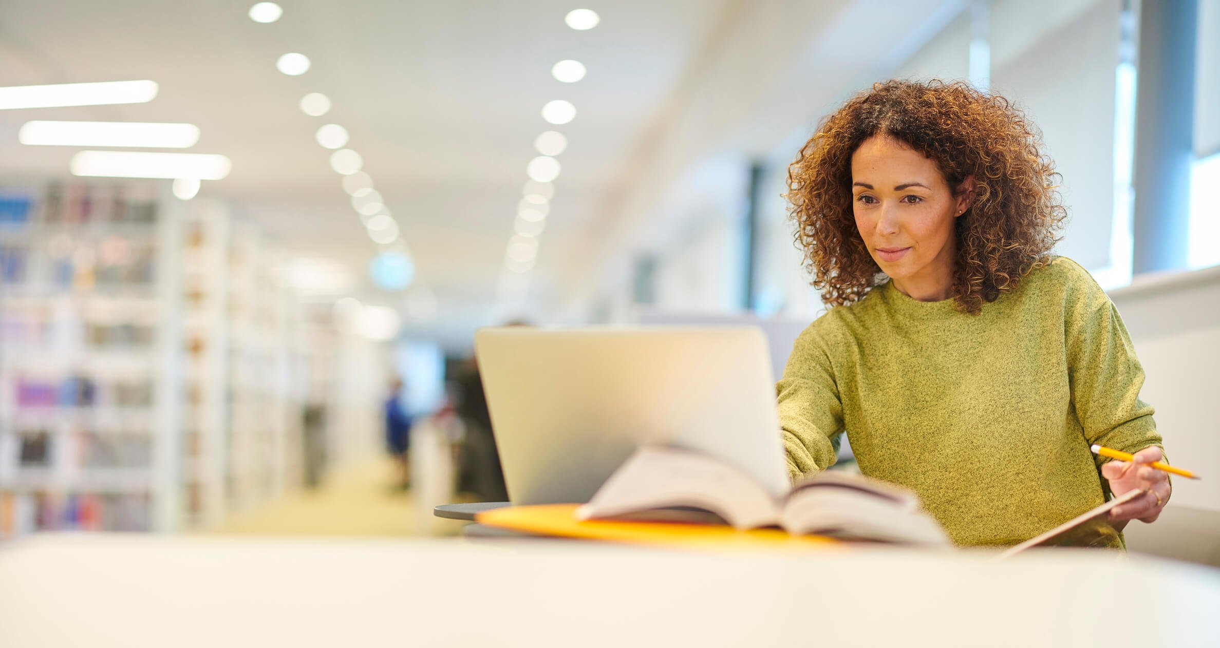 Woman sitting in library, working on her laptop