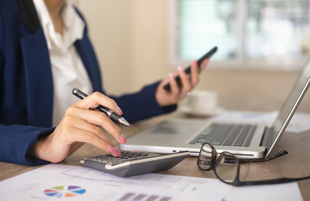 Businesswoman typing on a calculator at a desk