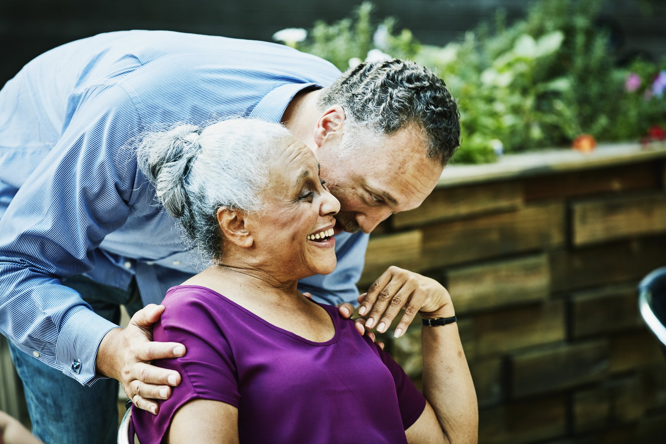 Man hugging and kissing mom before outdoor dinner party