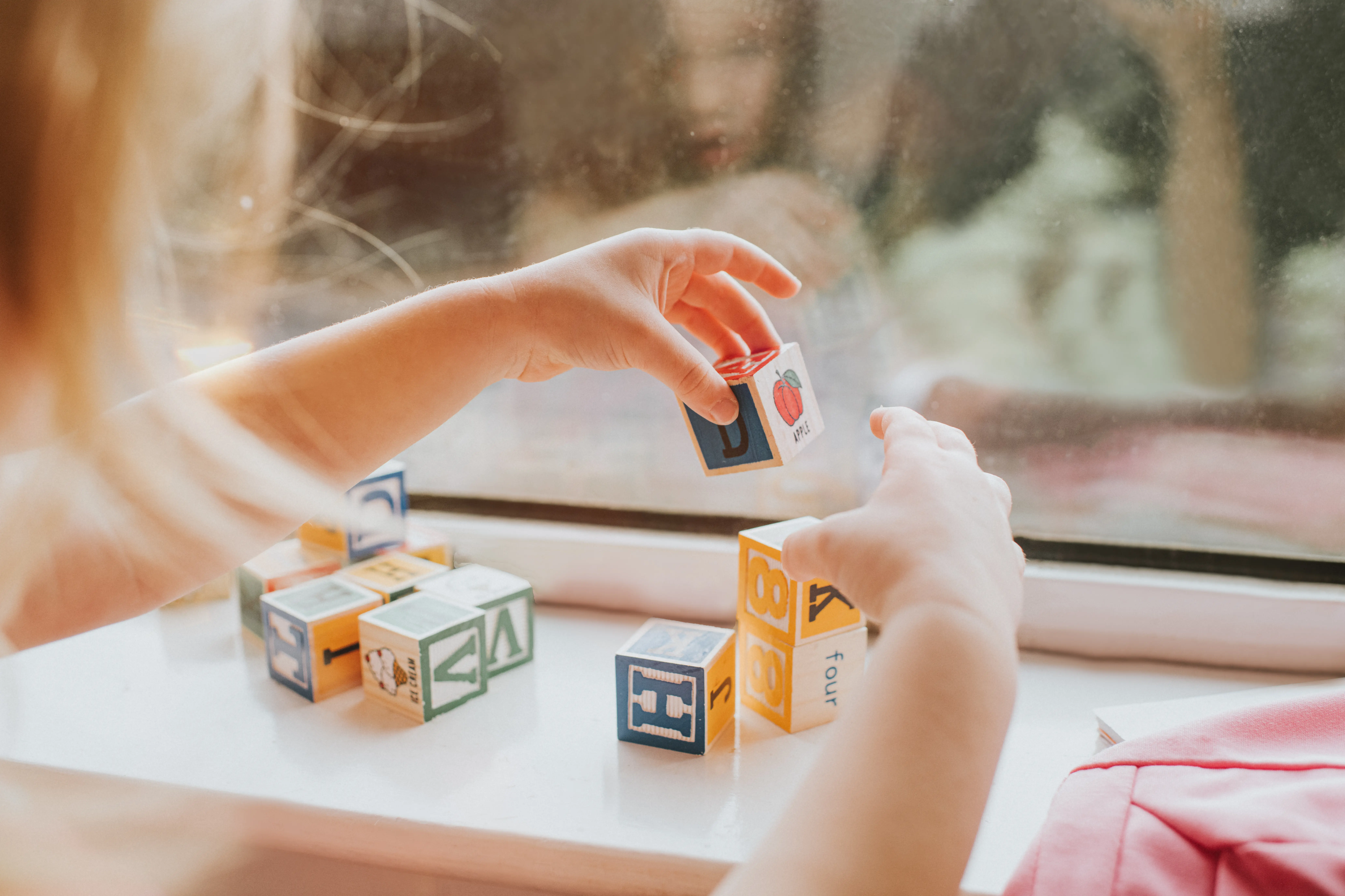 A happy child playing with colorful blocks that highlight the importance of affordable childcare expenses